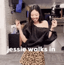 a woman in a black off the shoulder top and a leopard print skirt is dancing .