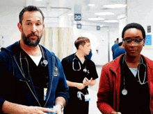a man and a woman standing in a hospital hallway with the number 20 on the wall