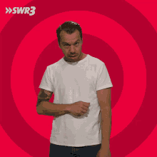 a man with his hands on his hips is standing in front of a red circle with swr3 written on it