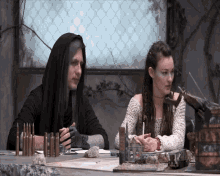 a man and a woman are sitting at a table with bullets on it and a sign that says " bullets " on it