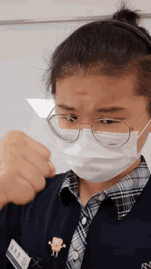 a woman wearing a face mask and glasses has a spongebob pin on her shirt