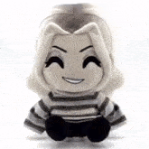 a stuffed animal with a striped shirt is sitting on a white surface .