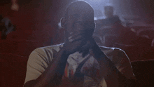 a man in a university of utah shirt sits in a dark theater