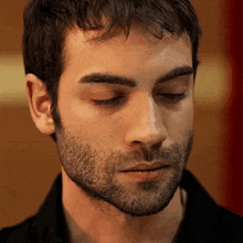 a close up of a man 's face with his eyes closed and a beard
