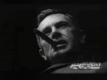 a man is smoking a cigar in a black and white photo with a few letters visible