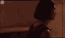 a woman in a red dress is standing in a room looking at herself in the mirror .