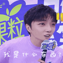 a man wearing a purple shirt is holding a microphone with chinese characters on it