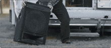 a man is carrying a large speaker in front of a white van