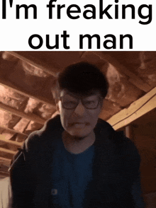 a man wearing glasses is making a funny face with the words i 'm freaking out man behind him