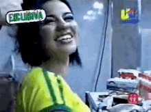 a woman wearing a yellow and green shirt is smiling with a sign that says exclusiva on her head