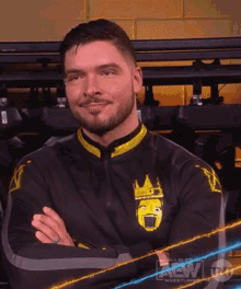 a man with his arms crossed is wearing a black and yellow jacket with a crown on it