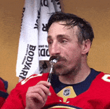 a man in a red jersey is eating a piece of food