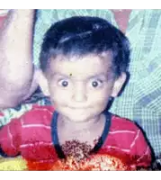 a young boy wearing a red striped shirt is smiling for the camera