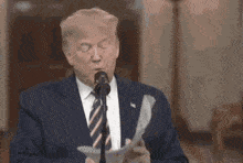 donald trump speaking into a microphone with his eyes closed