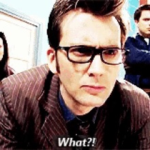 a man wearing glasses and a suit is looking at the camera and saying what ?