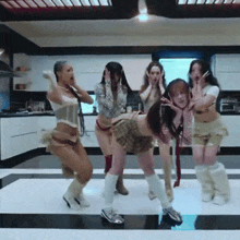 a group of women are dancing in a kitchen with their hands on their faces