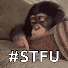 a baby chimpanzee is laying on a blanket and pointing at something .