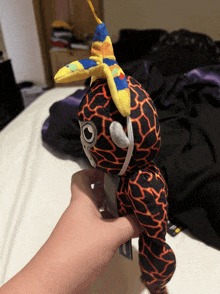 a person is holding a stuffed animal that looks like a giraffe with a hat on