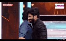 two men are hugging each other on a screen that says behindwoods tv