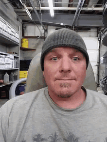 a man wearing a beanie looks at the camera in a garage .