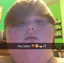 a young boy is taking a selfie with the words hey babe written on his face