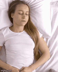 a young woman is sleeping on a bed with her eyes closed .