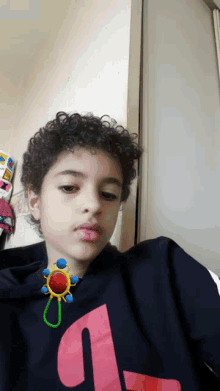 a young boy with curly hair is wearing a black shirt with the letter l on it