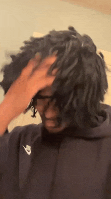 a person is touching a person 's hair while wearing a black hoodie .