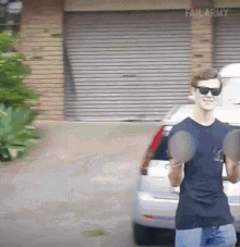 a man wearing sunglasses is holding a pair of dumbbells in front of a garage door that says failarmy
