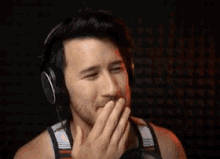 a shirtless man wearing headphones and a mustache is making a funny face .