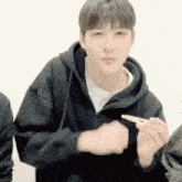 a man in a black hoodie is holding a chopstick in his hand and making a funny face .