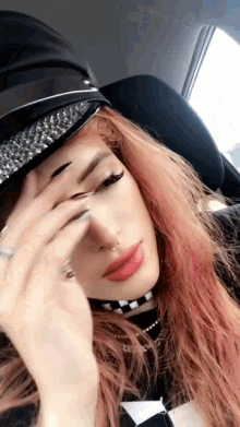 a woman with red hair is wearing a hat and choker .