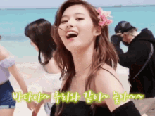 a woman with a flower in her hair is smiling on the beach .
