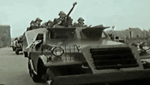 a black and white photo of a military vehicle with soldiers on top .