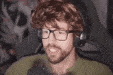 a man with a beard and glasses is wearing headphones .