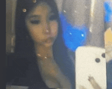 a woman is taking a selfie with her cell phone in front of a mirror .