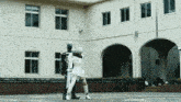 a man and a woman standing in front of a white building