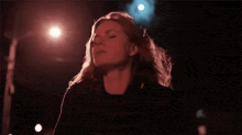a woman with long blonde hair is standing in front of a stage at night .