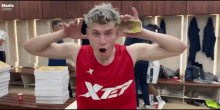 a man wearing a red xtep shirt holds a bottle in front of his face