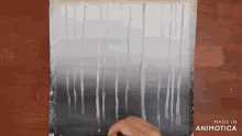 a person is painting on a piece of paper that says made in animatica on the bottom