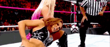 two women are wrestling in a wrestling ring while a referee watches .