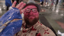 a man wearing glasses and a hat is waving