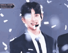 a man in a suit and tie is smiling while confetti falls around him .
