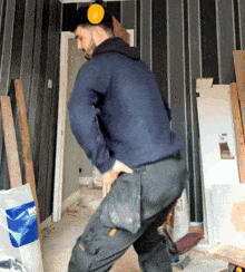a man wearing ear muffs is standing in a room with a bag of h & s on the floor