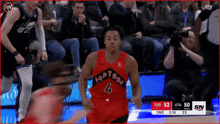a basketball player wearing a red raptors jersey is running on the court