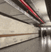 a person is walking down a hallway with red pipes