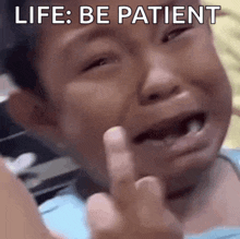 a little boy is crying and giving the middle finger with the words life be patient below him