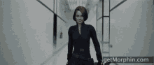 a woman in a black suit is standing next to a man in a hallway with the website getmorphin.com visible