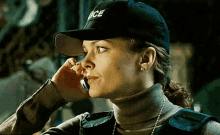 a woman wearing a police hat and a turtleneck is talking on a cell phone .
