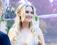 a woman in a white dress with a plunging neckline is smiling